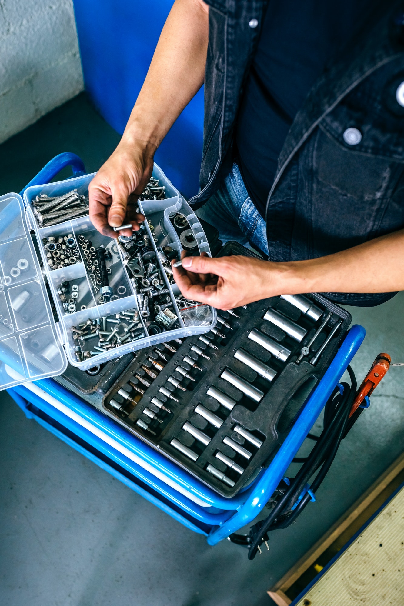 Mechanic's hands choosing screws from a tool box
